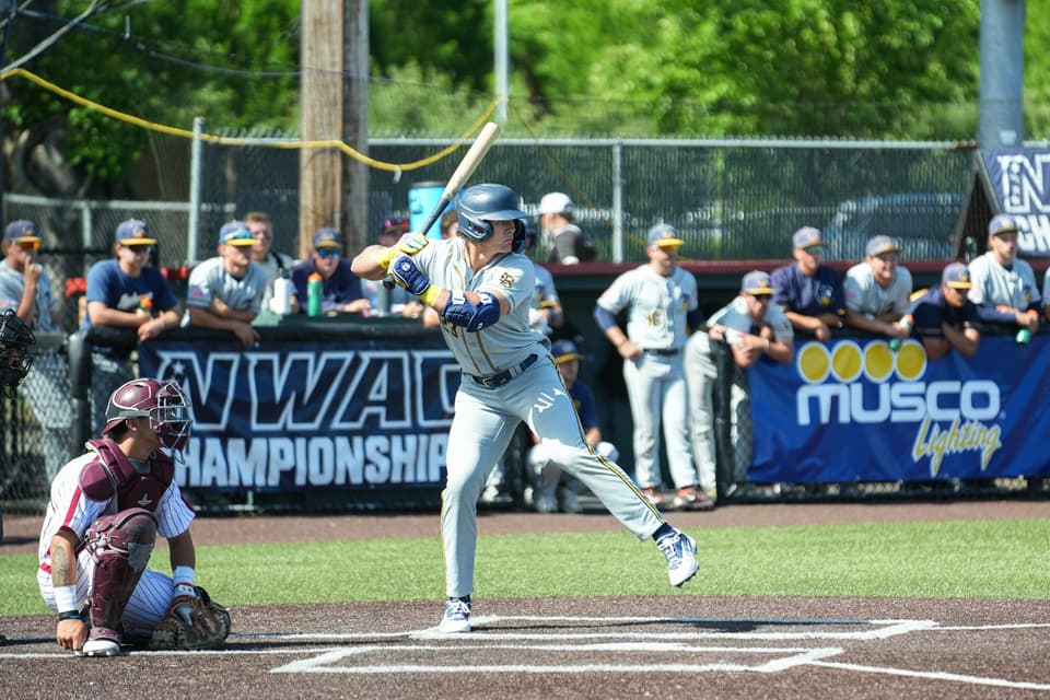 Linn-Benton hitter swinging as the Pierce catcher crouches behind home plate at the NWAC Championship