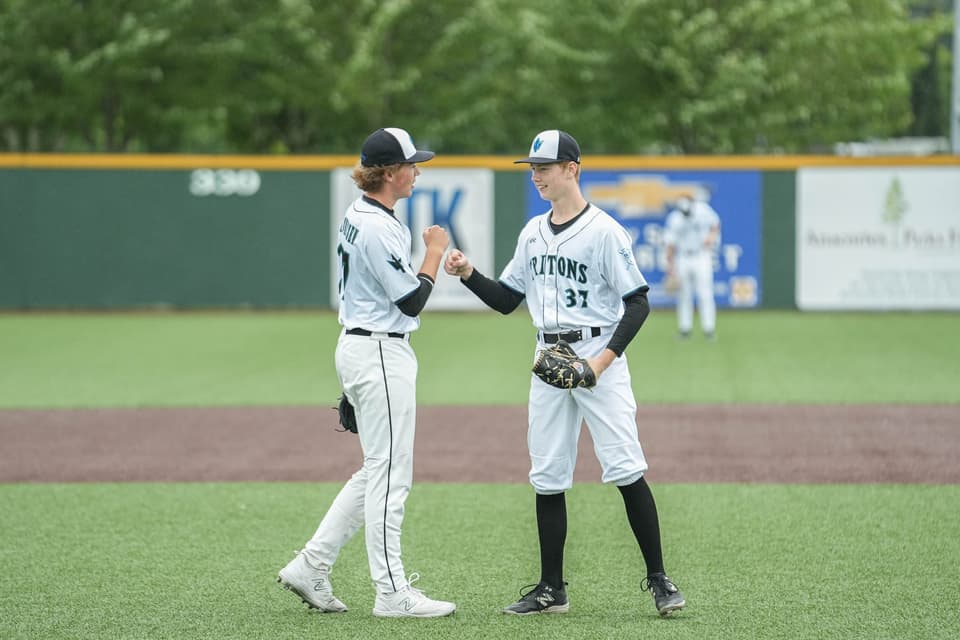 Two baseball teammates in gray uniforms meeting on the mound at the 2026 Showcase
